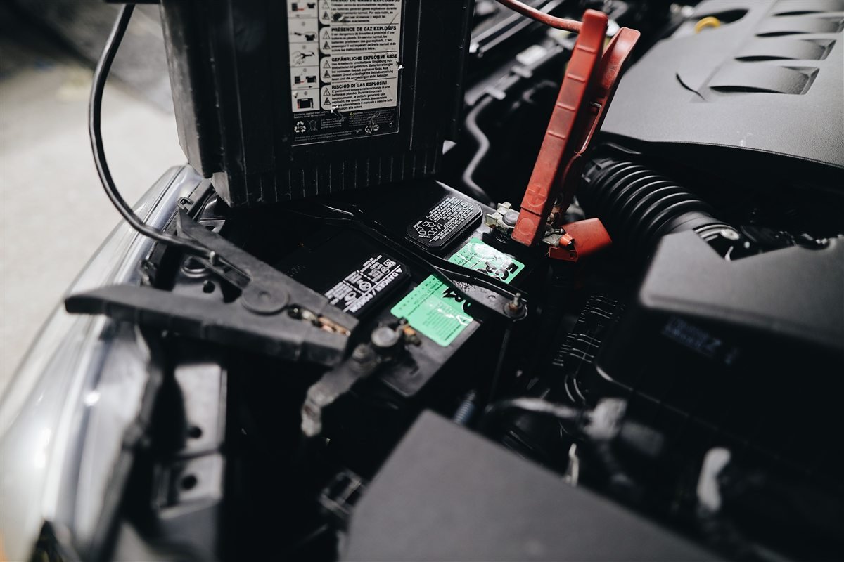 Battery charger and clamps connected to a car battery.