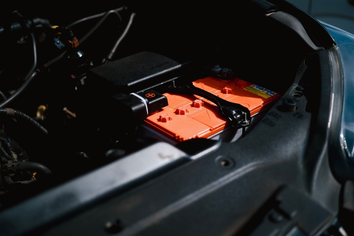 Red car battery installed inside an engine bay.