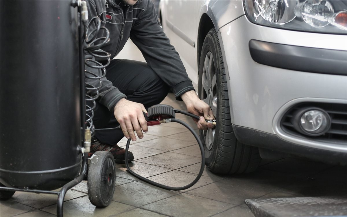 Mechanic connecting an air hose to a car tire.